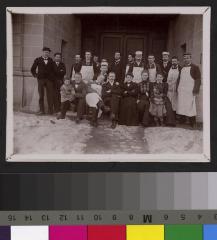 Volée d'étudiants avec leurs professeurs sous le porche de l'Ecole de médecine. On reconnaît, a gauche de l'image, les mains dans les poches et chapeau sur la tête, le professeur Henri Preisig. Quelques portraiturés portent la casquette de leur société…