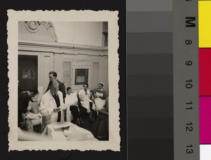 Le Prof. Jules Taillens est dans une salle de cours avec deux patients, entouré d'étudiants, d'une infirmière et probablement d'assistants.