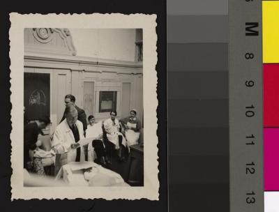 Le Prof. Jules Taillens est dans une salle de cours avec deux patients, entouré d'étudiants, d'une infirmière et probablement d'assistants.