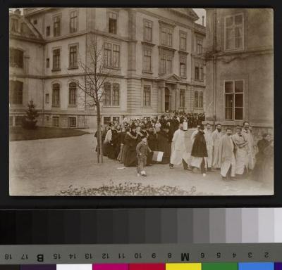 Manifestation non identifiée. On reconnaît au premier rang la Doctoresse Charlotte Olivier, à sa droite le Docteur André Guisan et au deuxième rang, avec la barbe le Dr Paul Vuilleumier. Les participants à la manifestation sortent de l'Hôpital cantonal…