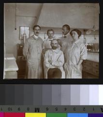 Portrait du Dr Bruno Galli-Valerio, assis, au centre, entouré par ses collaborateurs, dans un laboratoire.